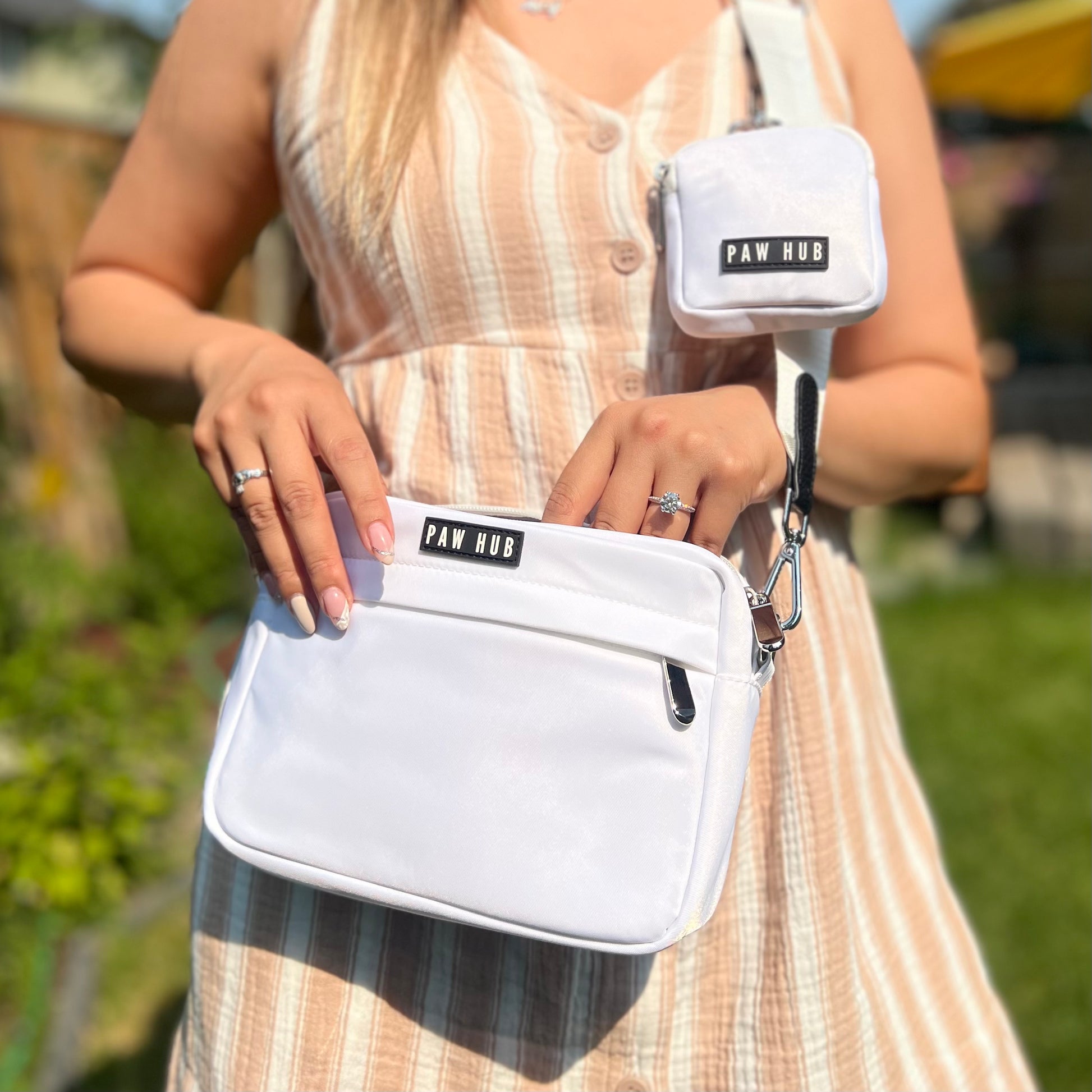 Person holding a white bag with 'PAW HUB' branding outdoors.
